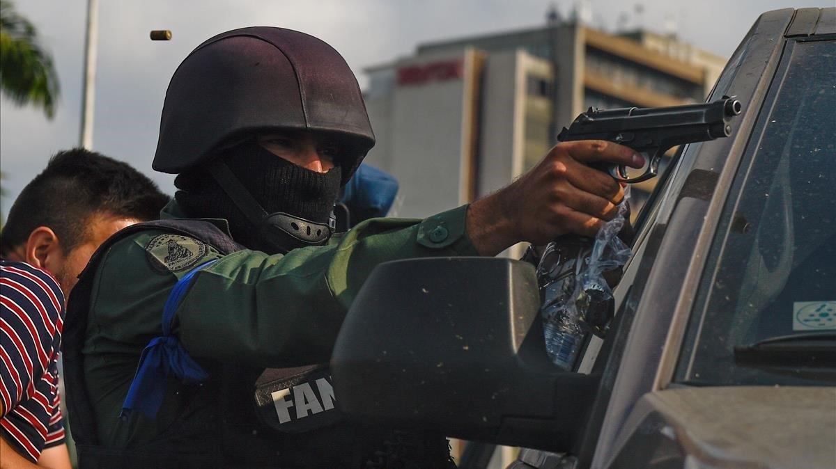 Un miembro de la Guardia Nacional Bolivariana que se unió al líder opositor venezolano y autoproclamado presidente en funciones, Juan Guaido, apunta con su arma mientras repelen a las fuerzas leales al presidente Nicolás Maduro.