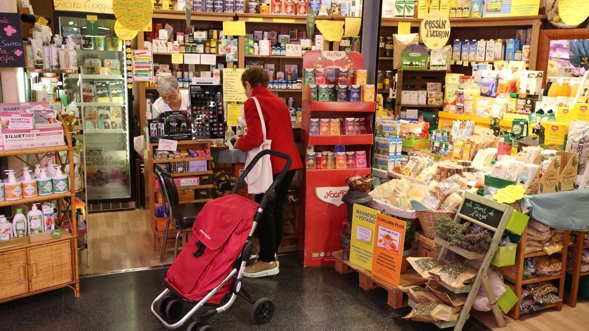 Una dependienta atiende a una clienta en un puesto de herboristería del mercado municipal de Lesseps de Barcelona.