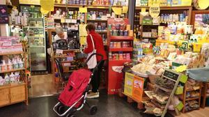 Una dependienta atiende a una clienta en un puesto de herboristería del mercado municipal de Lesseps de Barcelona.