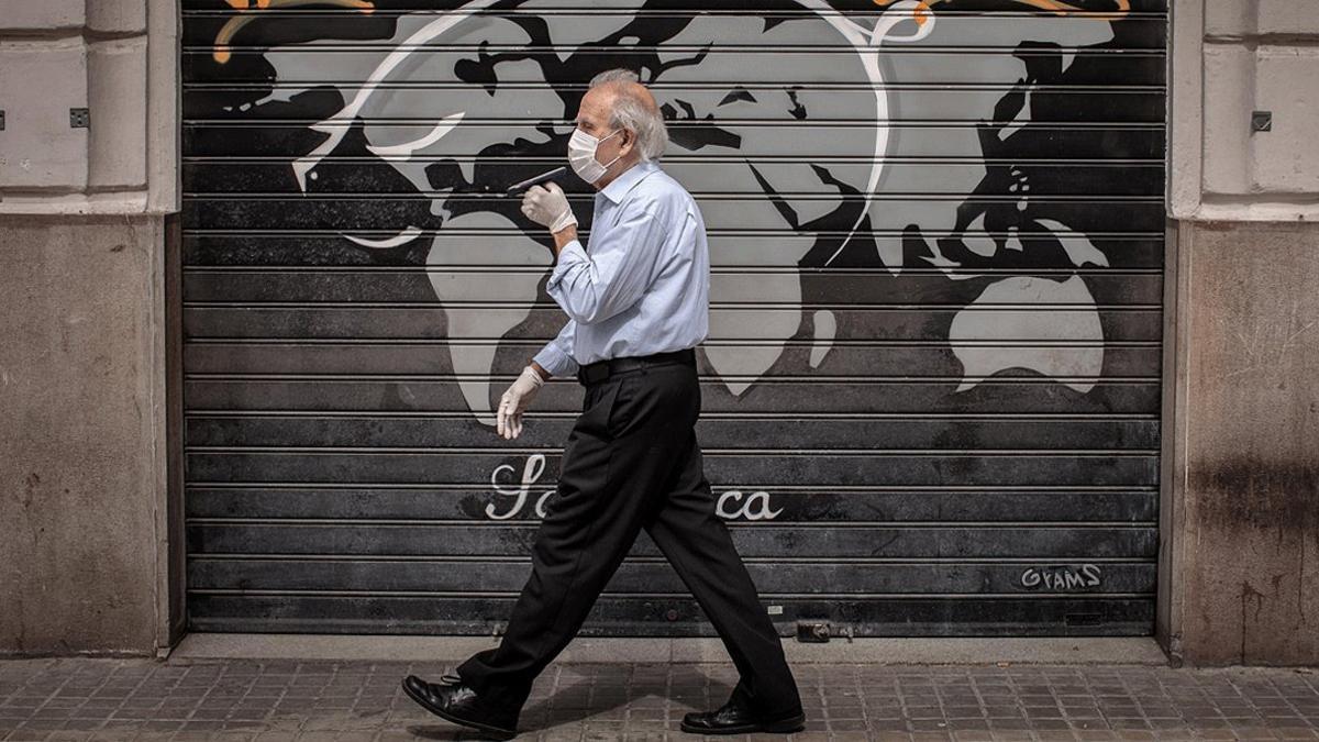 Un hombre con mascarilla pasa junto a comercio cerrado, en València, el 9 de mayo