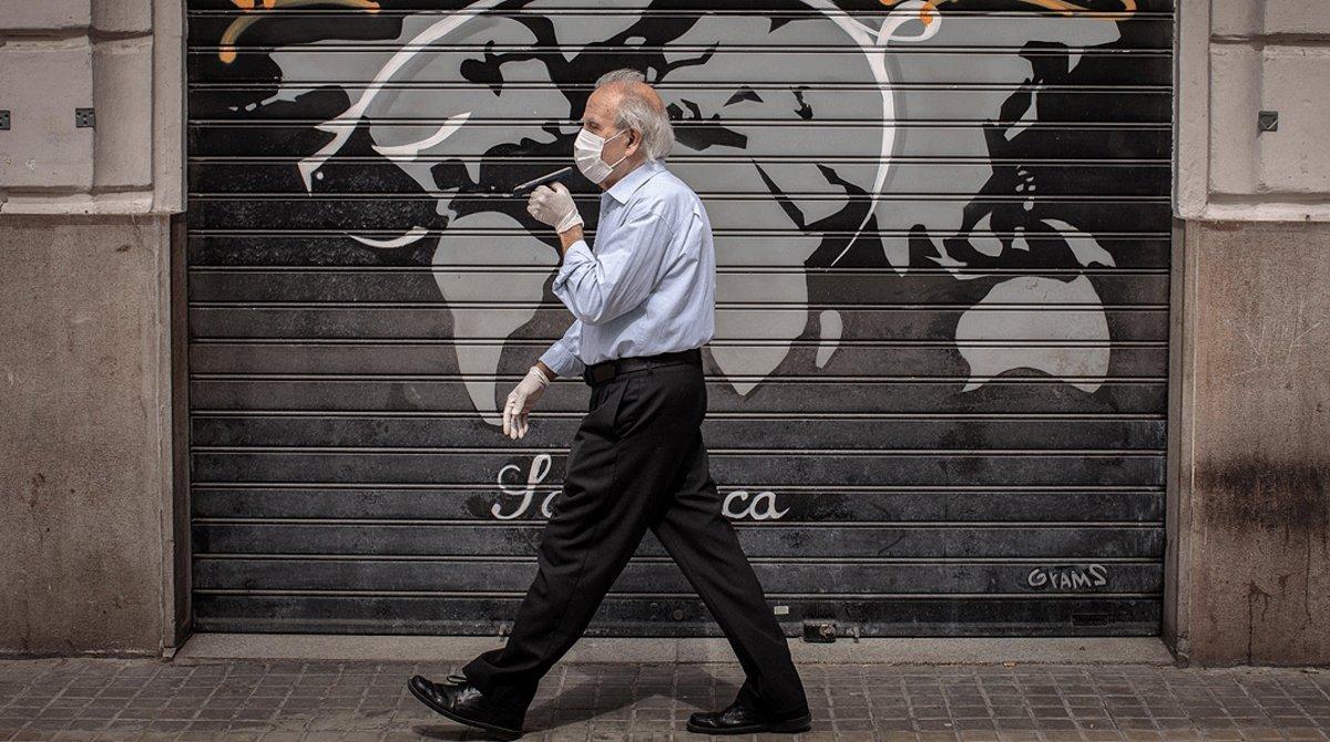 Un hombre con mascarilla pasa junto a comercio cerrado, en València, el 9 de mayo.