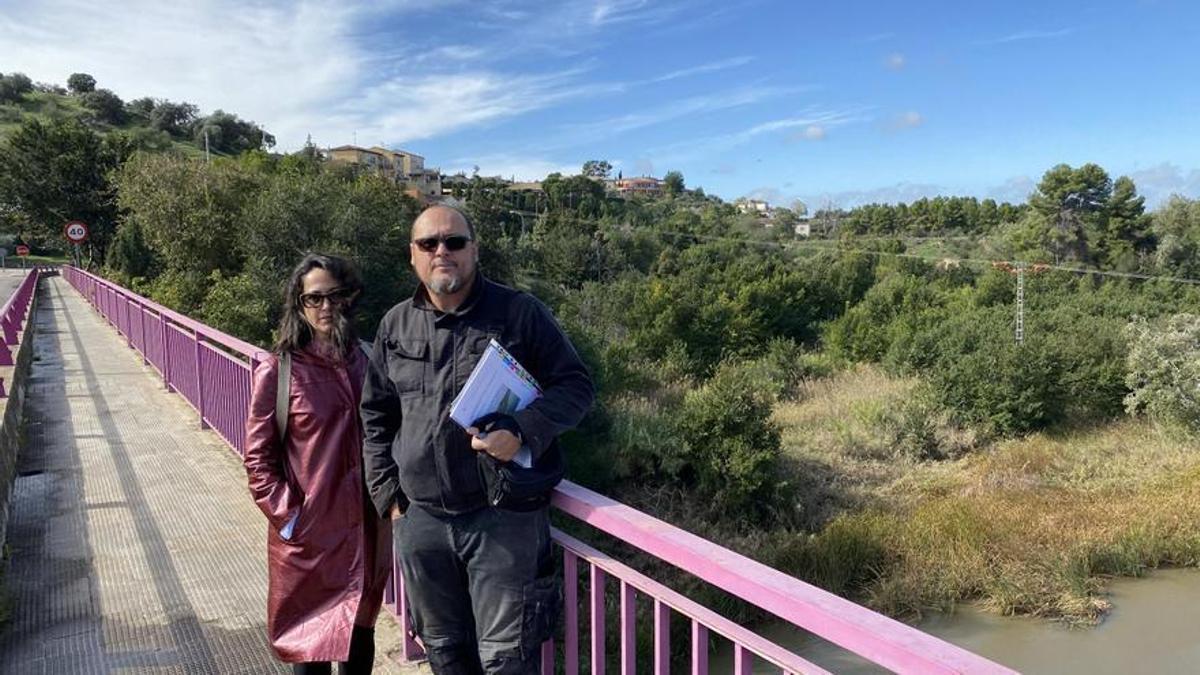 Carlos Gutiérrez y Gema López Briones, miembros de la asociación de vecinos de La Cava, en el puente que cruza hacia la parcela donde se realizará la actuación urbanística.