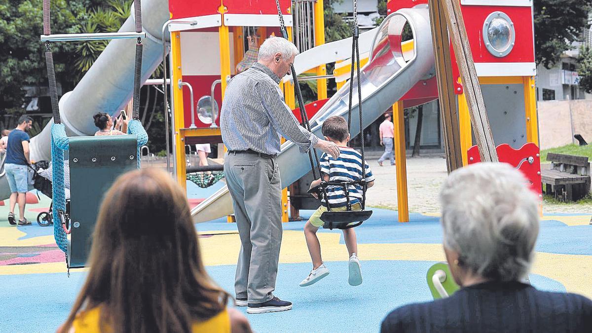 Un abuelo empuja a su nieto en un columpio en la plaza de la Independencia de Vigo.