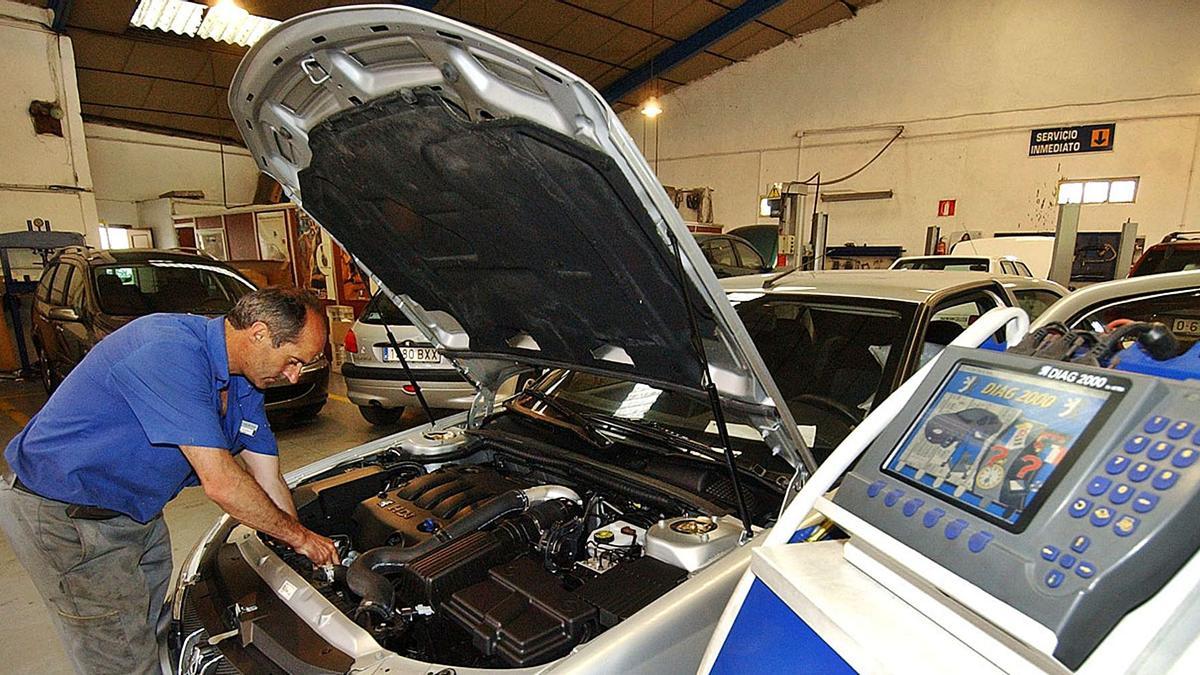 Un operari de taller revisant el motor d’un vehicle