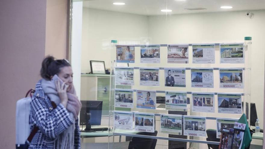 Una chica pasea ante el escaparate de una inmobiliaria en València.