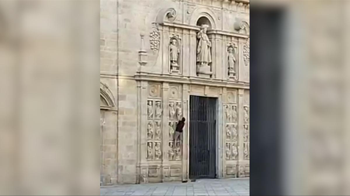 Turista escalando por la Puerta Santa de la Catedral de Santiago