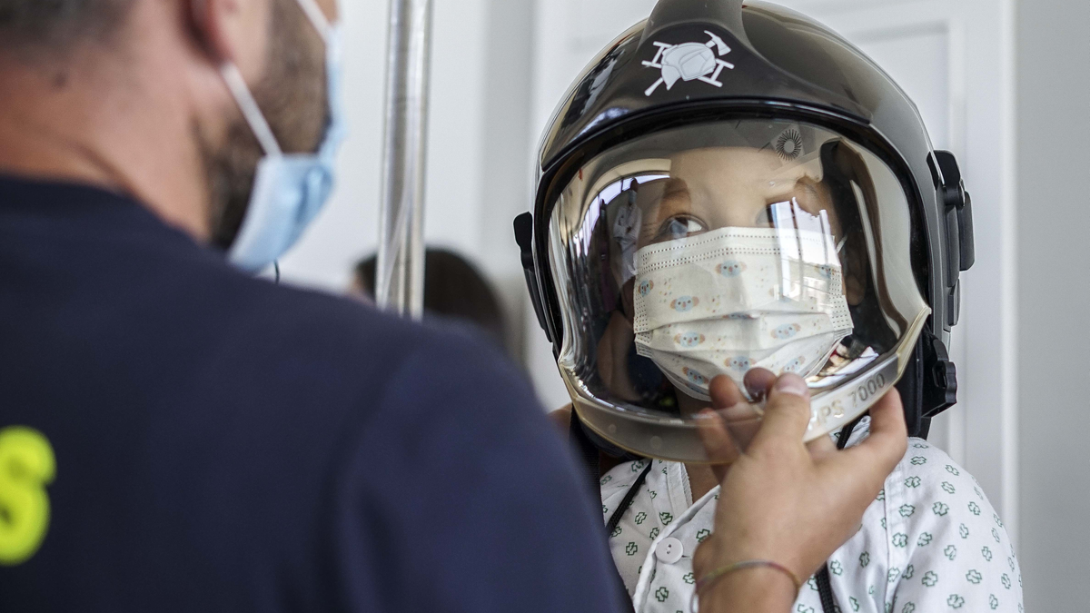 Un niño, con casco de bombero.