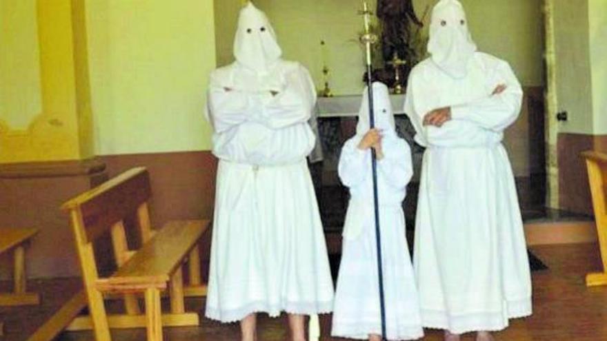 Tres cofrades en la iglesia de Villarrín, descalzos y ataviados con la túnica y caperuza blanca. | Cedida