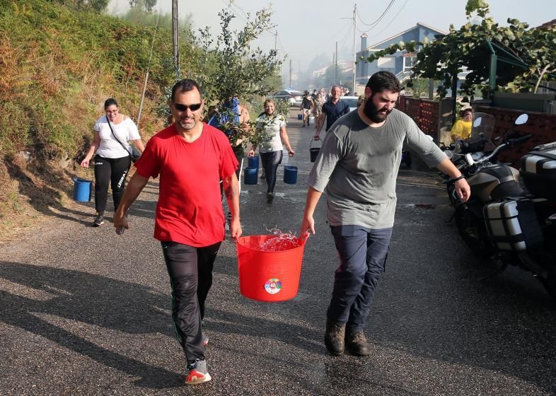 Los vecinos ayudando a sofocar las llamas en el virulento incendio de agosto. | MARTA G. BREA