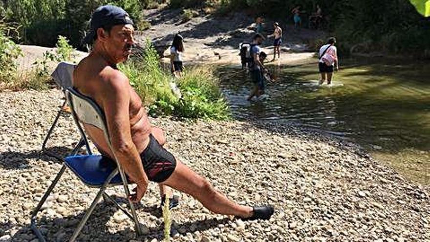 Un banyista pren el sol a tocar de l&#039;aigua esperant la resta de la família, que ha anat a inspeccionar l&#039;entorn