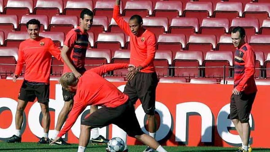 Xavi, Busquets y Henry observan los ejercicios de estiramiento de Gudjohnsen, ayer.