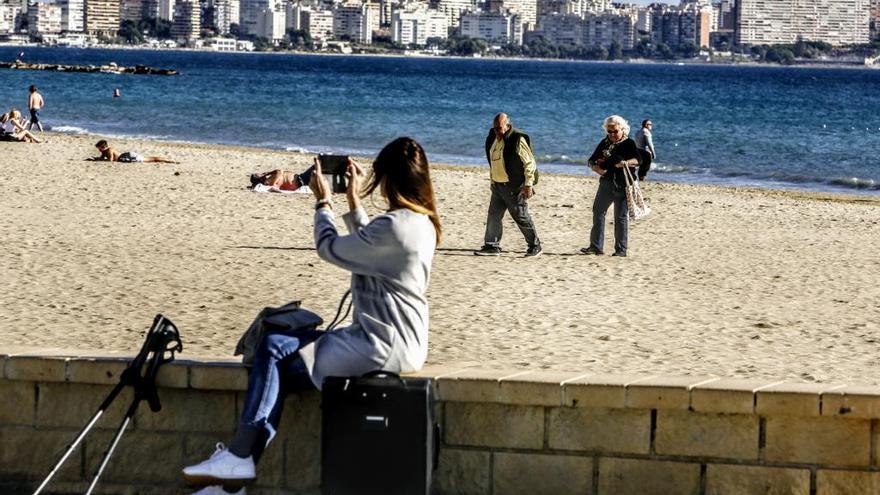 Una joven sacando fotos en la playa del Postiguet de Alicante a las 14.30 horas de hoy martes