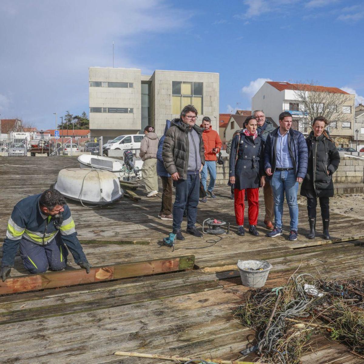 Miembros del PSOE ante el muelle de Pau, dañado por el temporal.