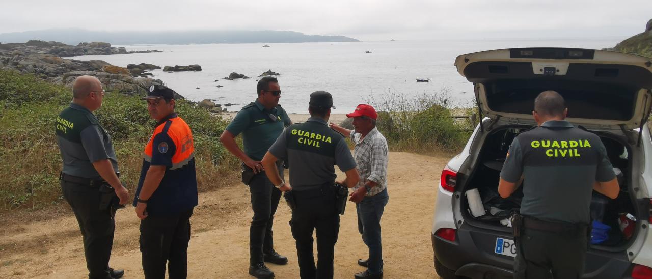 La Guardia Civil con el vecino que salió a pescar con el hombre desaparecido, durante las labores de búsqueda