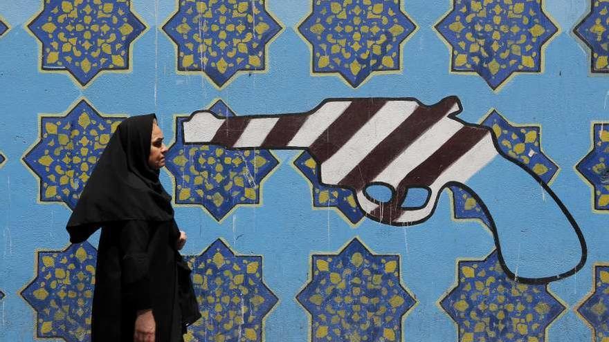 Una mujer iraní camina frente a un mural pintado en el exterior de la Embajada de EE UU en Teherán. // AFP