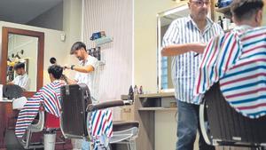 Dos jóvenes se cortan el pelo en una peluquería de Madrid