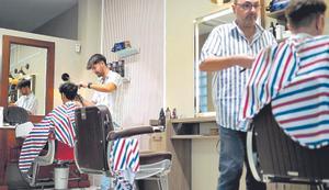 Dos jóvenes se cortan el pelo en una peluquería de Madrid