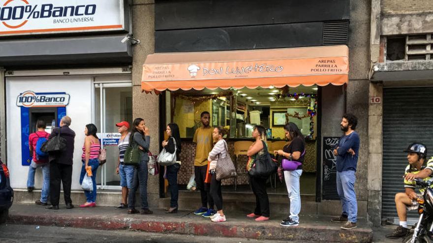 Ciudadanos venezolanos hacen cola ante un banco.