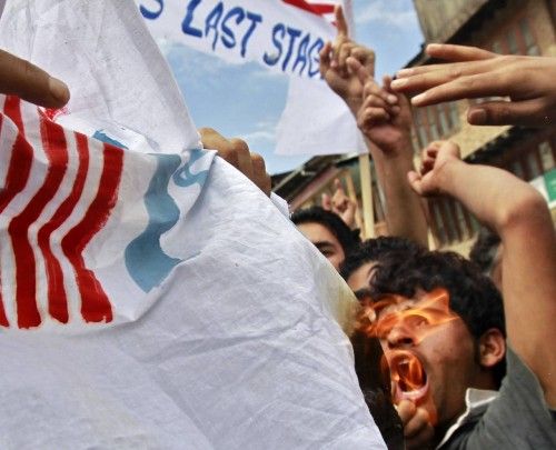 A Kashmiri Muslim protester shouts slogans in front a burning American and Israeli flag, that have been joint together, during a strike in Srinagar