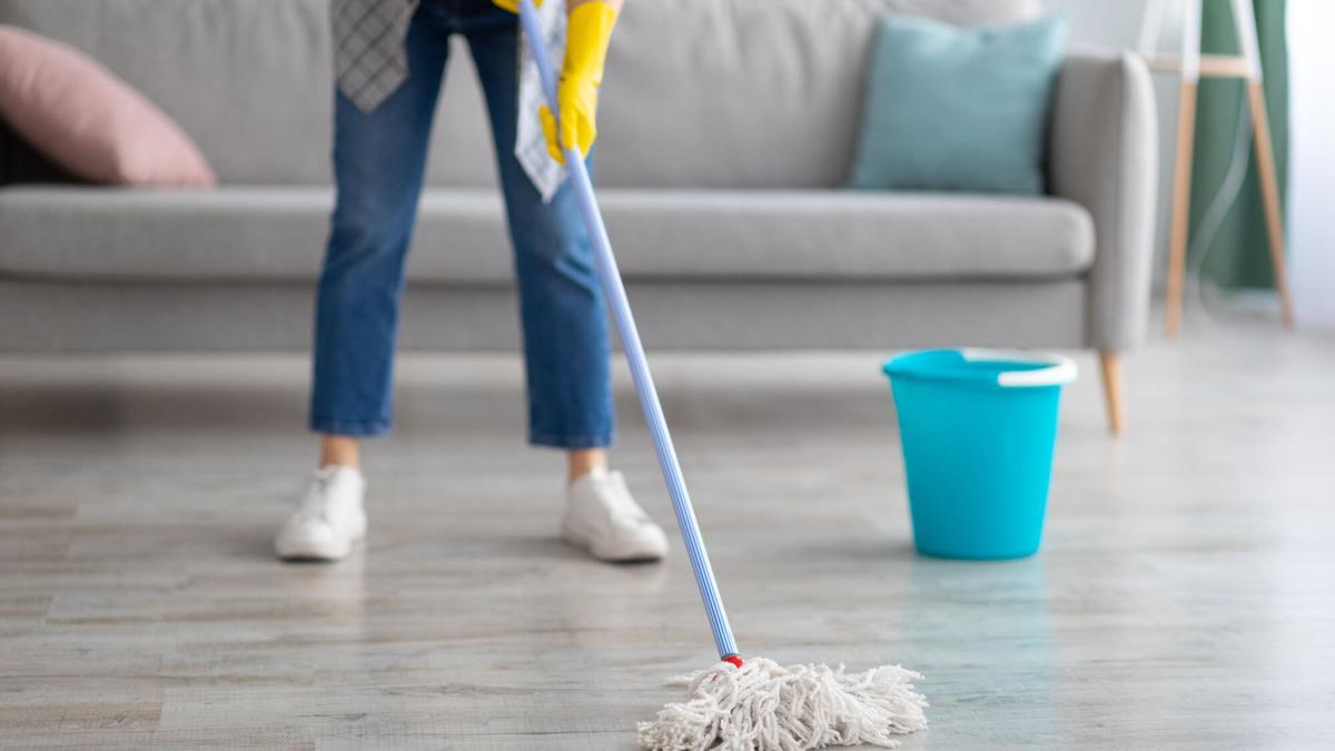 Persona limpiando el suelo de su hogar.