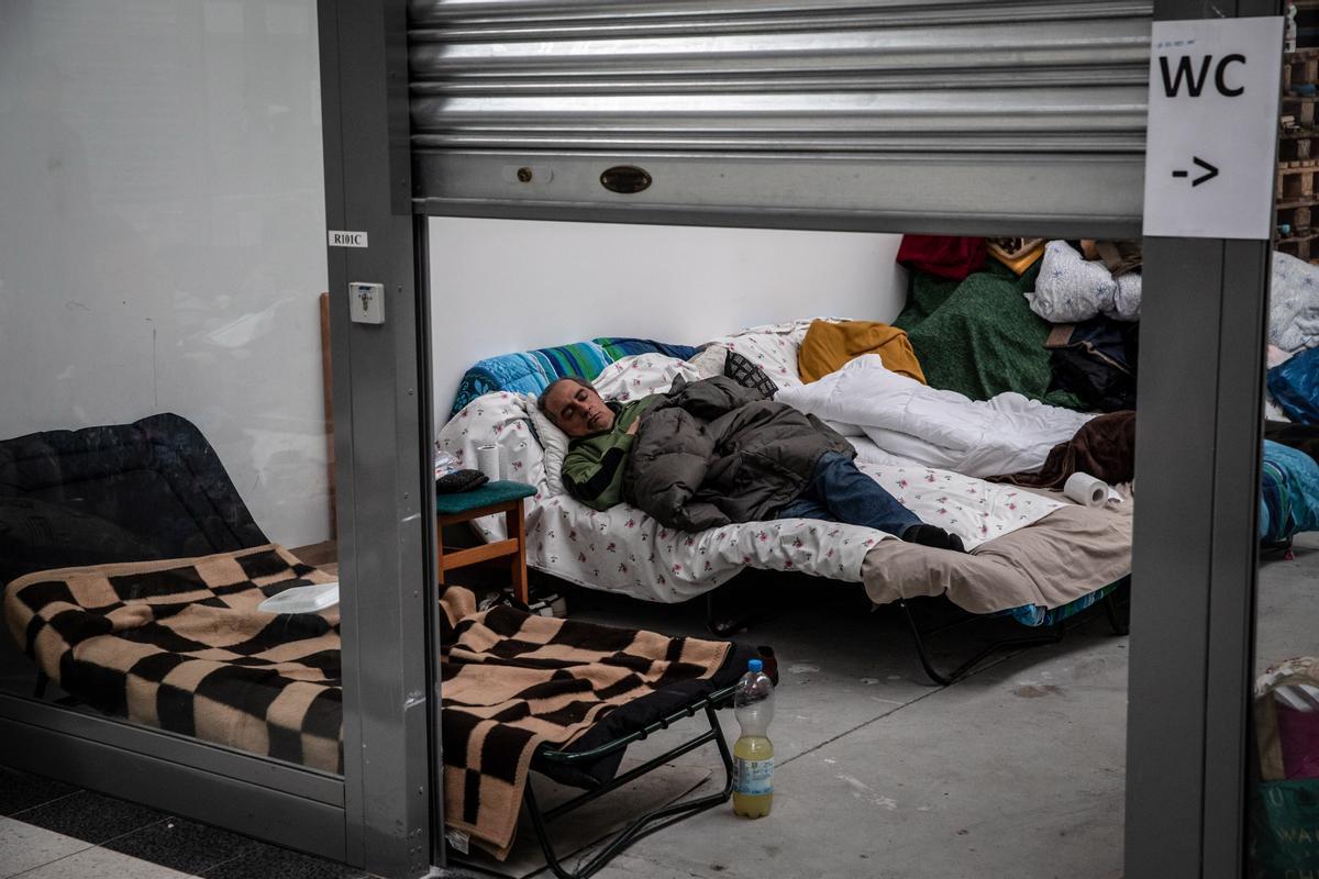 Un refugiado ucraniano descansa en una cama improvisada en un refugio temporal de acogida ubicado en un centro comercial en Korczowa, Polonia. 