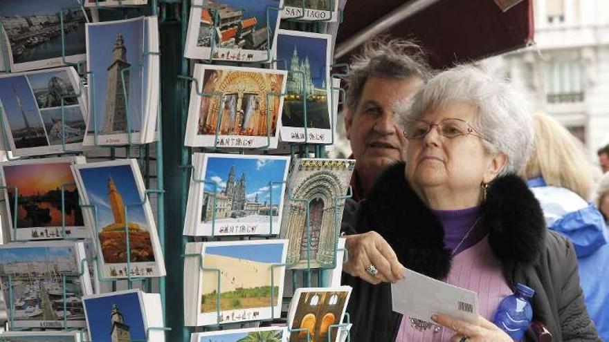 Turistas compran postales en una tienda de &#039;souvenirs&#039; de A Coruña. a. cruz