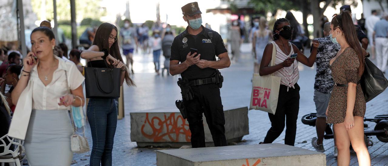 Un Policía Local de Palma informa a los viandantes de la obligatoriedad del uso de las mascarillas.