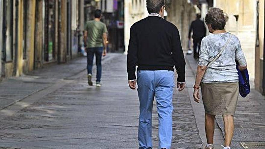 Una pareja de jubilados pasea por el casco antiguo.