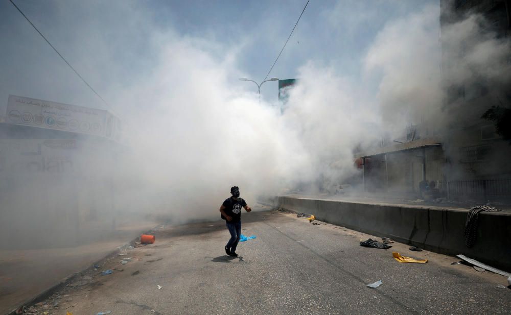 A Palestinian protester reacts to tear gas fired ...
