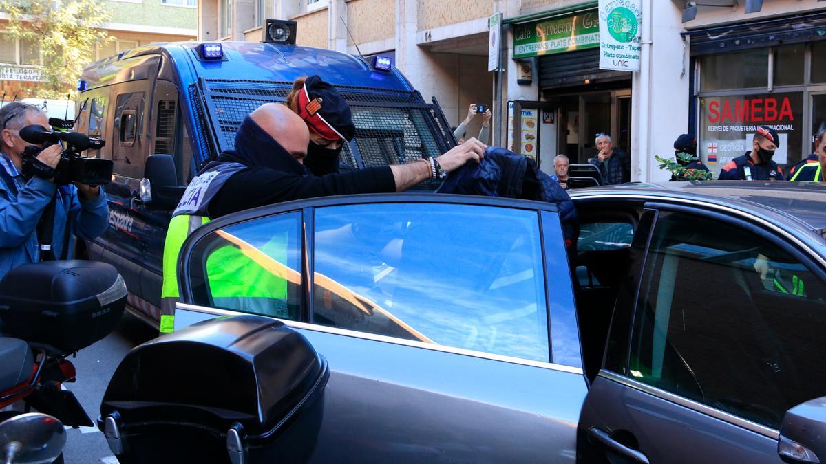 Agentes de la policía se llevan a un detenido tras el registro realizado en una empresa de paquetería de Barcelona