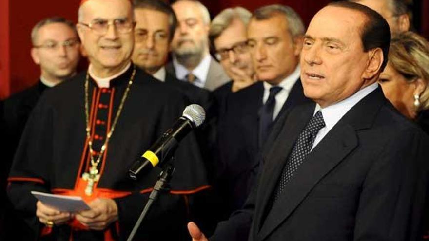 El primer ministro italiano, Silvio Berlusconi (d), y el secretario de Estado del Vaticano, Tarcisio Bertone (i), durante la inauguración de la exposición &quot;Il potere e la grazia&quot;, en el palacio Venezia de Roma.