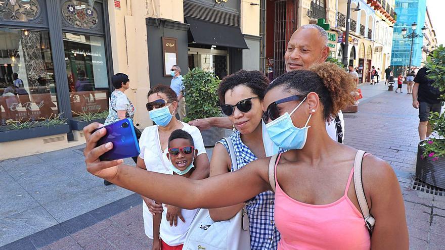 Una familia de turistas se hace una foto en la céntrica calle Alfonso de Zaragoza. | ÁNGEL DE CASTRO