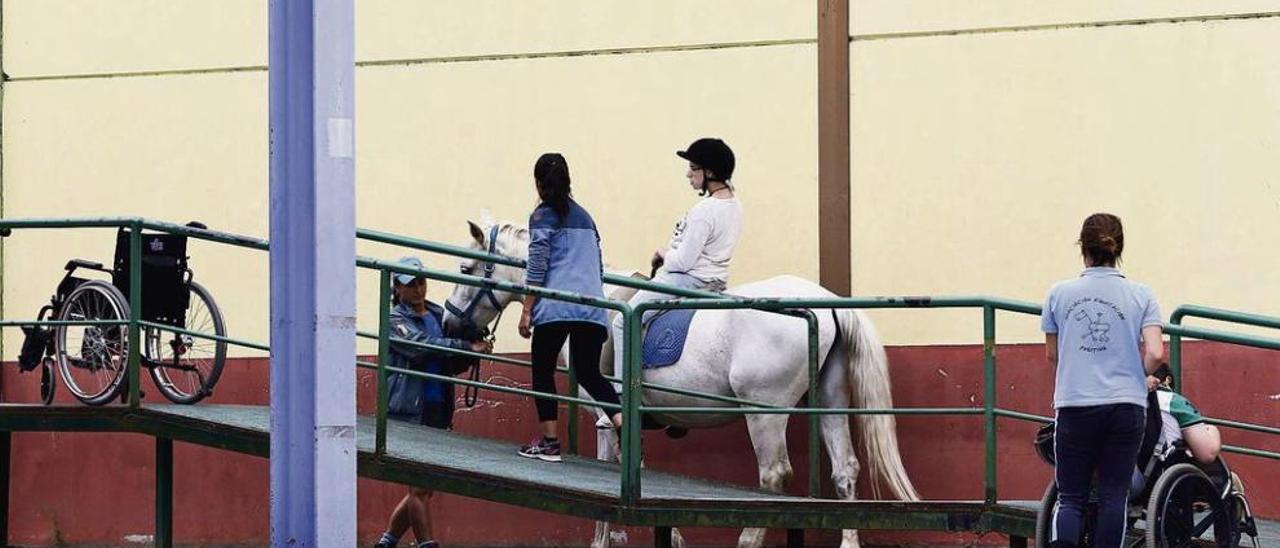 Sobre estas líneas, un grupo de pacientes y monitores de las terapias equinas. A la izquierda, Mónica Álvarez, psicóloga de la asociación.