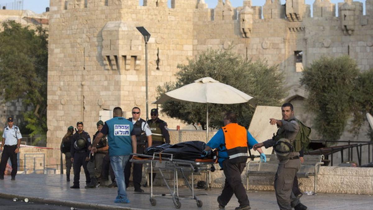 Agentes israelís trasladan el cadáver de un palestino, ante la puerta de Damasco, en Jerusalén este.