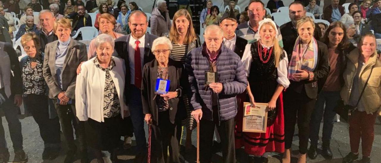 Infiesto rindió homenaje en el inicio de su tradicional Festival de la Avellana a los nonagenarios Consuelo Canto y Manuel de la Llana, en el centro de la imagen, los dos con un bastón; a su lado, a la derecha, los jóvenes designados como «Avellaneros del año», Iván González e Irene Medina, con traje tradicional. El alcalde de Piloña, Iván Allende, y la pregonera, Charo Pérez, aparecen tras los mayores homenajeados, acompañados por el resto de los ediles del concejo. | A. L.