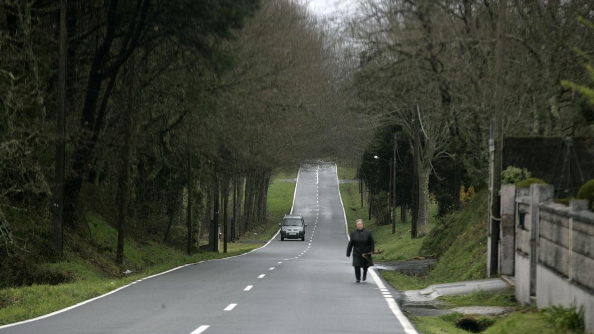 Una vecina pasea por la carretera en la zona en la que se va a crear la senda peatonal.