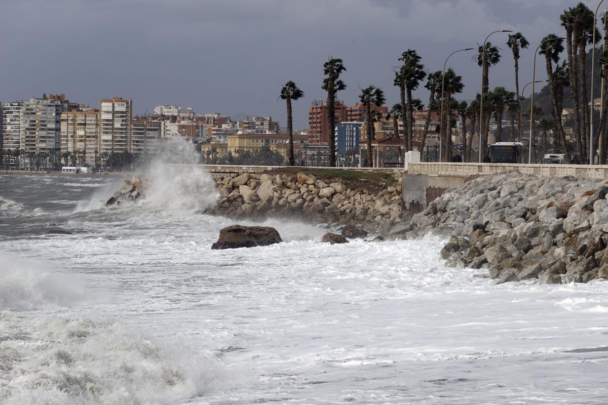 MLG 10-02-2023.-Varias personas intentan andar por la calle donde el temporal con vientos de 70 km/h y el litoral malagueño registra olas de tres metros.-ÁLEX ZEA
