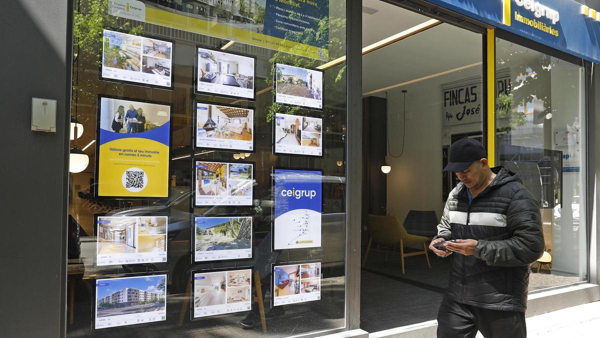 Un home davant l'aparador d'una immobiliària a Girona.