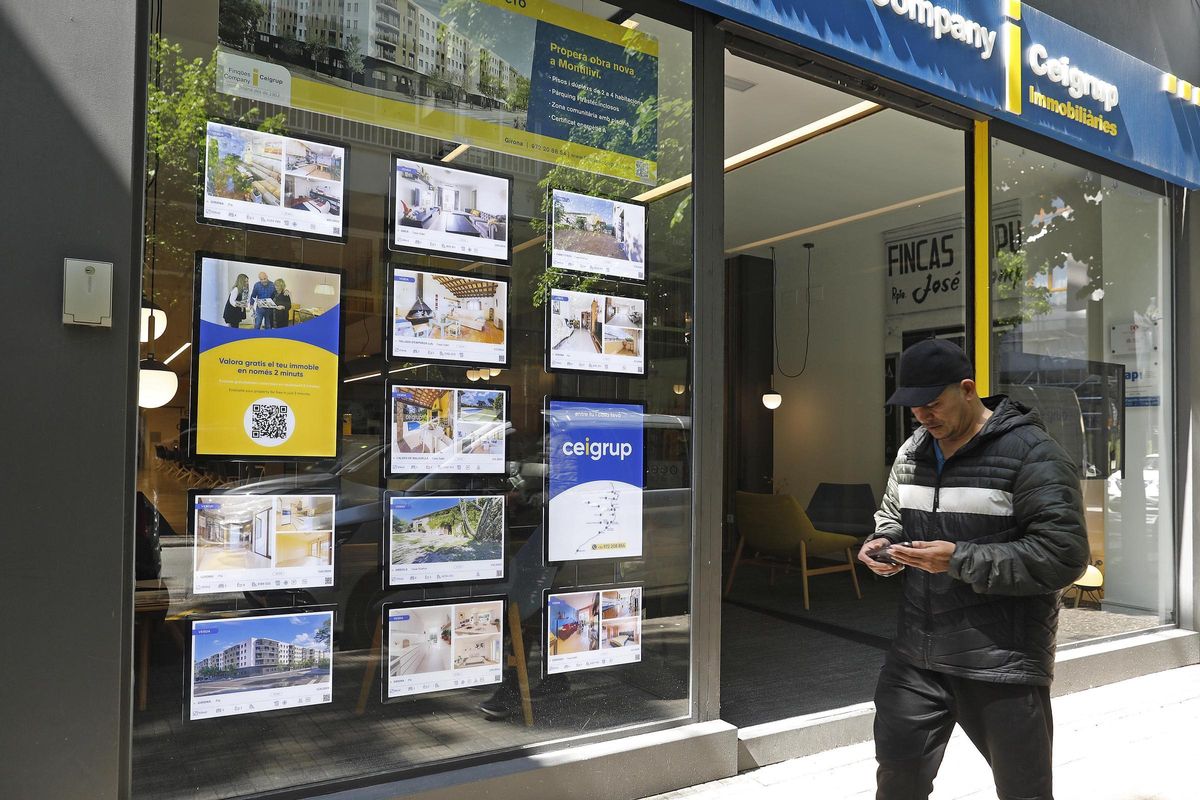 Un home davant l'aparador d'una immobiliària a Girona.