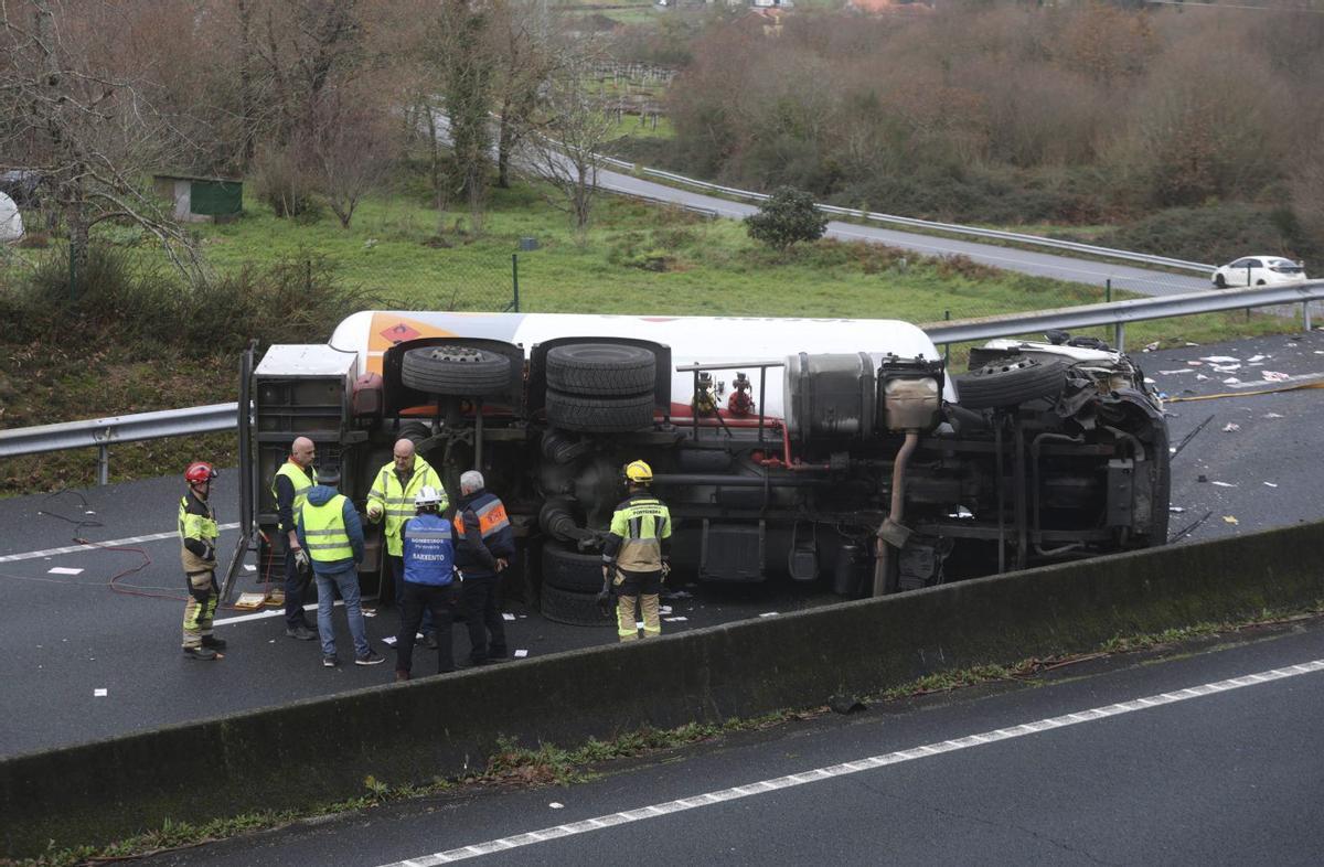 Varios efectivos de emergencias, junto al camión cisterna volcado.