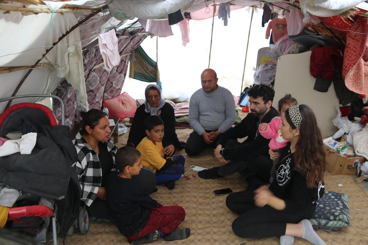 Un cooperante de Global Humanitaria conversa con una familia en su tienda de campaña.