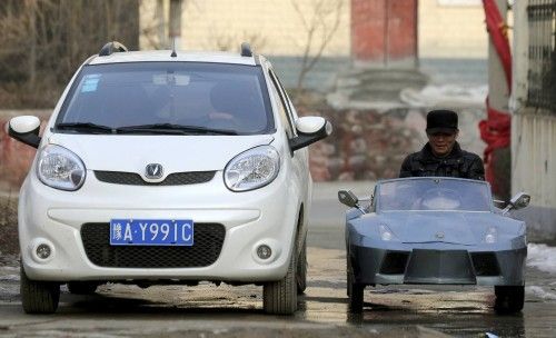 Guo, a farmer in his 50s, drives his self-made scale replica of a Lamborghini past a car on a street in Zhengzhou