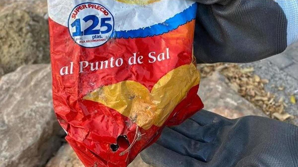 Hallan en las rocas del Postiguet una bolsa de patatas de más de 22 años.