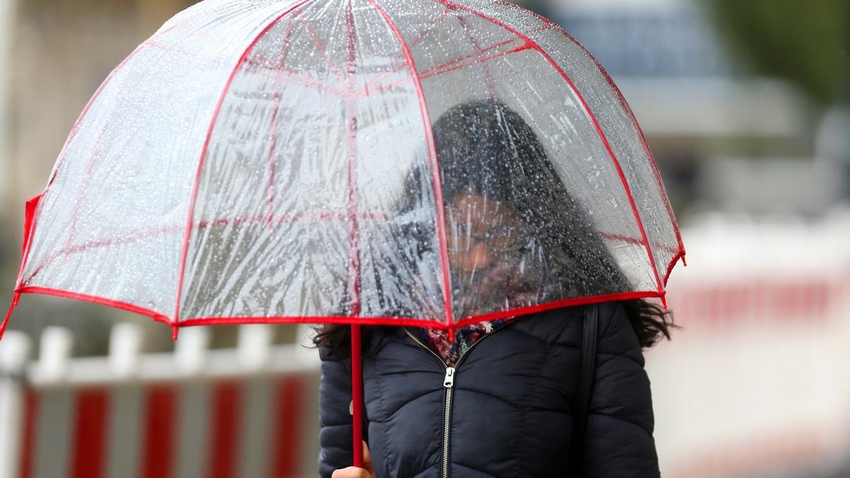 Un mujer se protege de la lluvia, este mediodía en Vigo