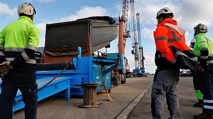 Un grupo de trabajadores observa un camión descargando abono en la cinta transportadora que lo meterá en la bodega de un barco. | M. Villamuza