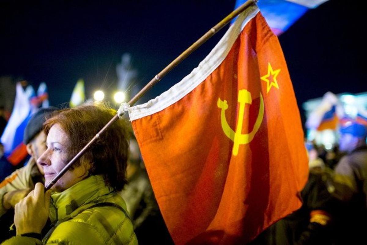 Una dona sosté una bandera soviètica a la plaça de Lenin, a Simferopol, aquest diumenge.