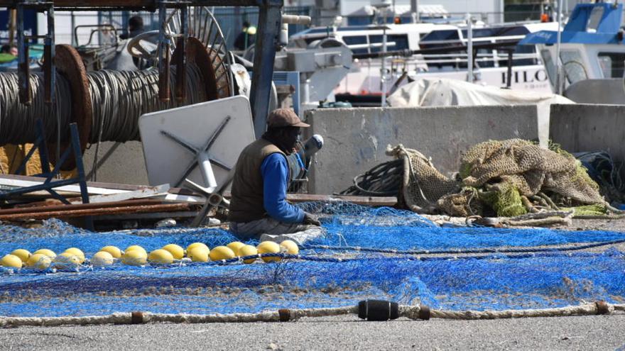 Un pescador repara las redes en el muelle situado frente a la Cofradía de Pescadores.