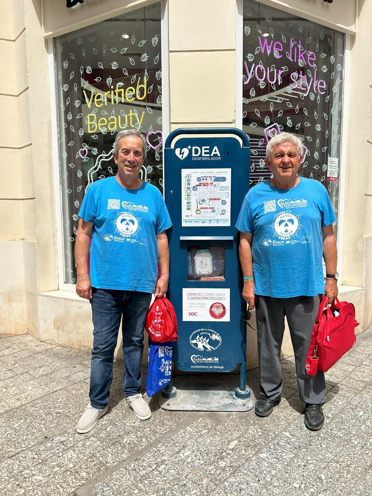 A la izquierda, Ramón Mora con Ángel García junto a uno de los 676 desfibriladores instalados en Málaga