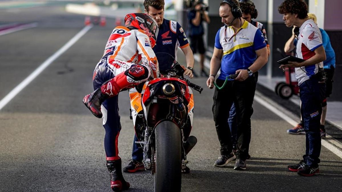 Marc Márquez se baja de su Honda, en Catar, ante uno de sus mecánicos y los técnicos de Michelin.