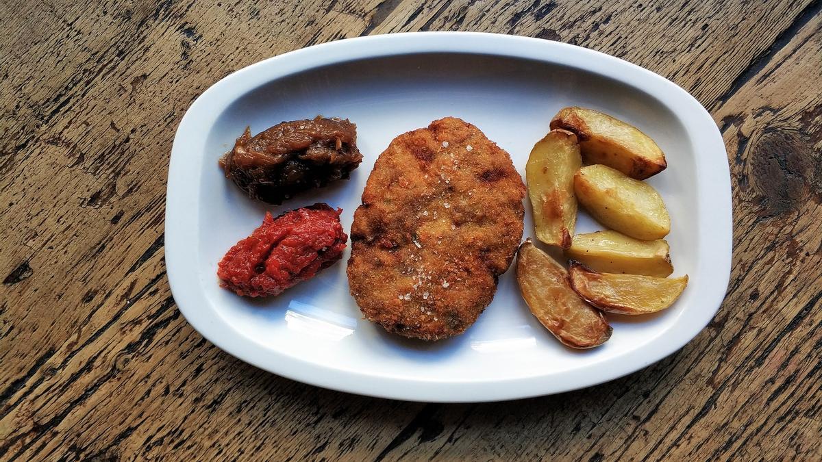 El plato de filete ruso con cebolla, patatas y compota de tomate.